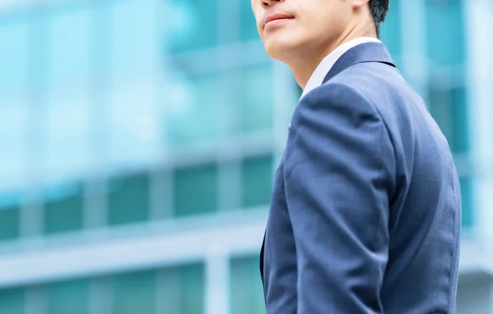 ビル街を背景に立つスーツ姿の営業担当者