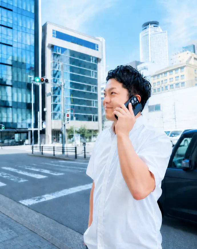オフィス街で電話をしながら外回りをするメンバー