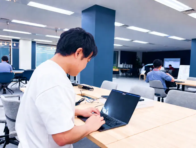 オフィスでノートパソコンに向かって作業するメンバー